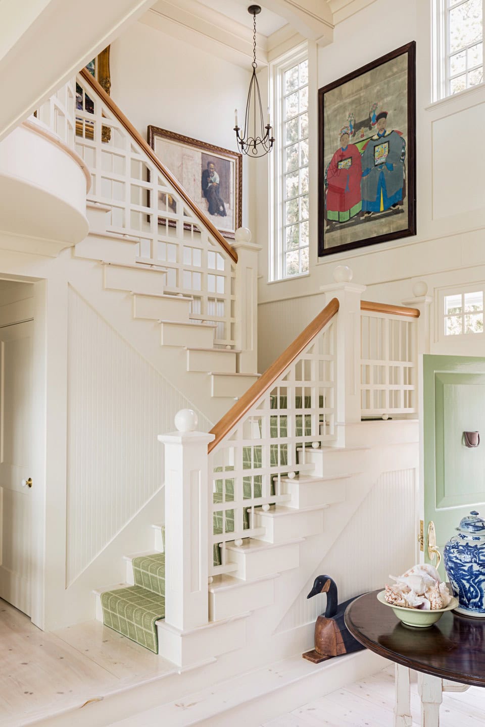 Bright interior staircase with white woodwork and large window, airy home decor.
